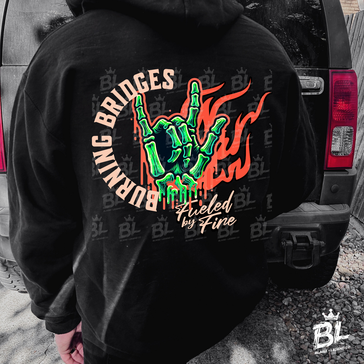 Burning Bridges hoodie with skeleton hand rock symbol, flames, 'Fueled by Fire' text, and Blaise + Legend Co. branding down the sleeve. Bold, edgy design for men and women.