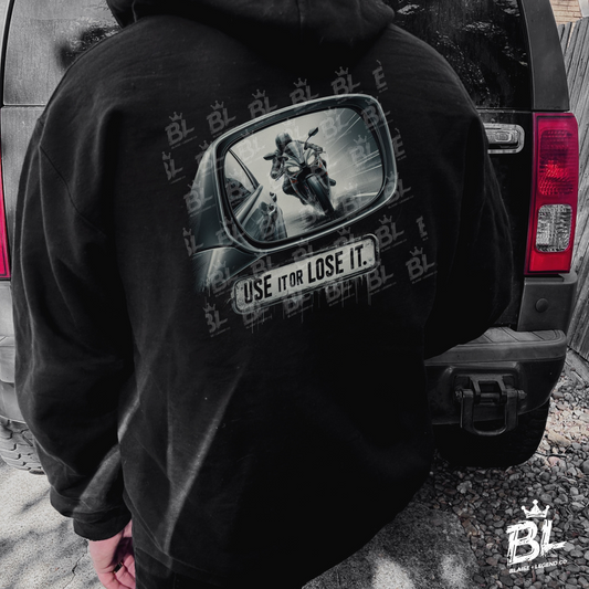 Unisex black hoodie featuring 'Use It or Lose It' design with car mirror and motorcycle graphic